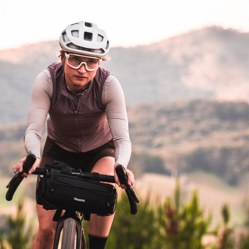 Skingrowsback Overnighter Handlebar Bag — young female cyclist tackling mountainous terrain on a gravel bike