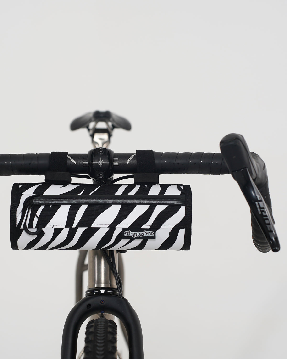 skingrowsback little lunch handlebar bag black and white zebra print on a titanium gravel bike with a white background