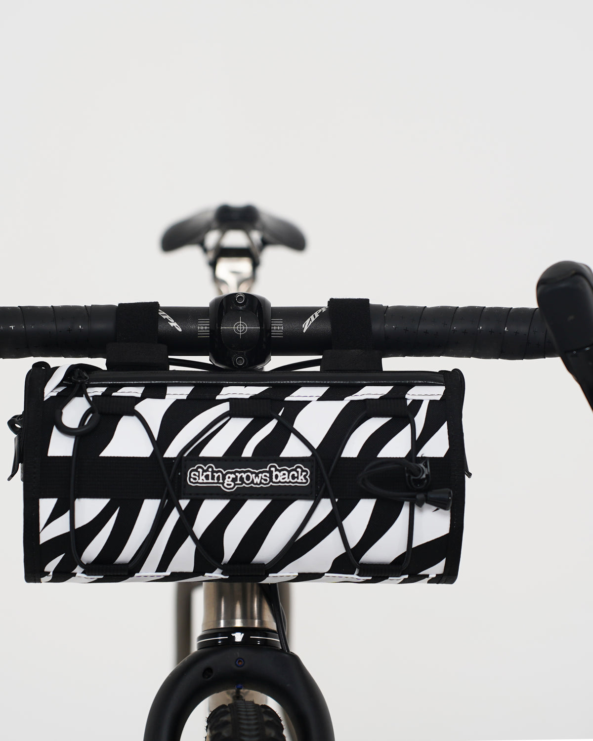 skingrowsback lunchbox handlebar bag black and white zebra print on a titanium gravel bike with a white background