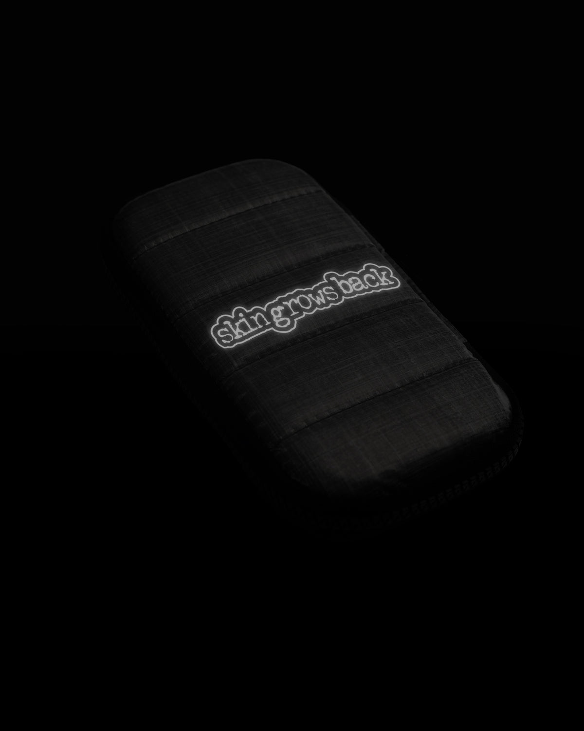skingrowsback phone jacket with dyneema silver zip case with reflective logo on a black background