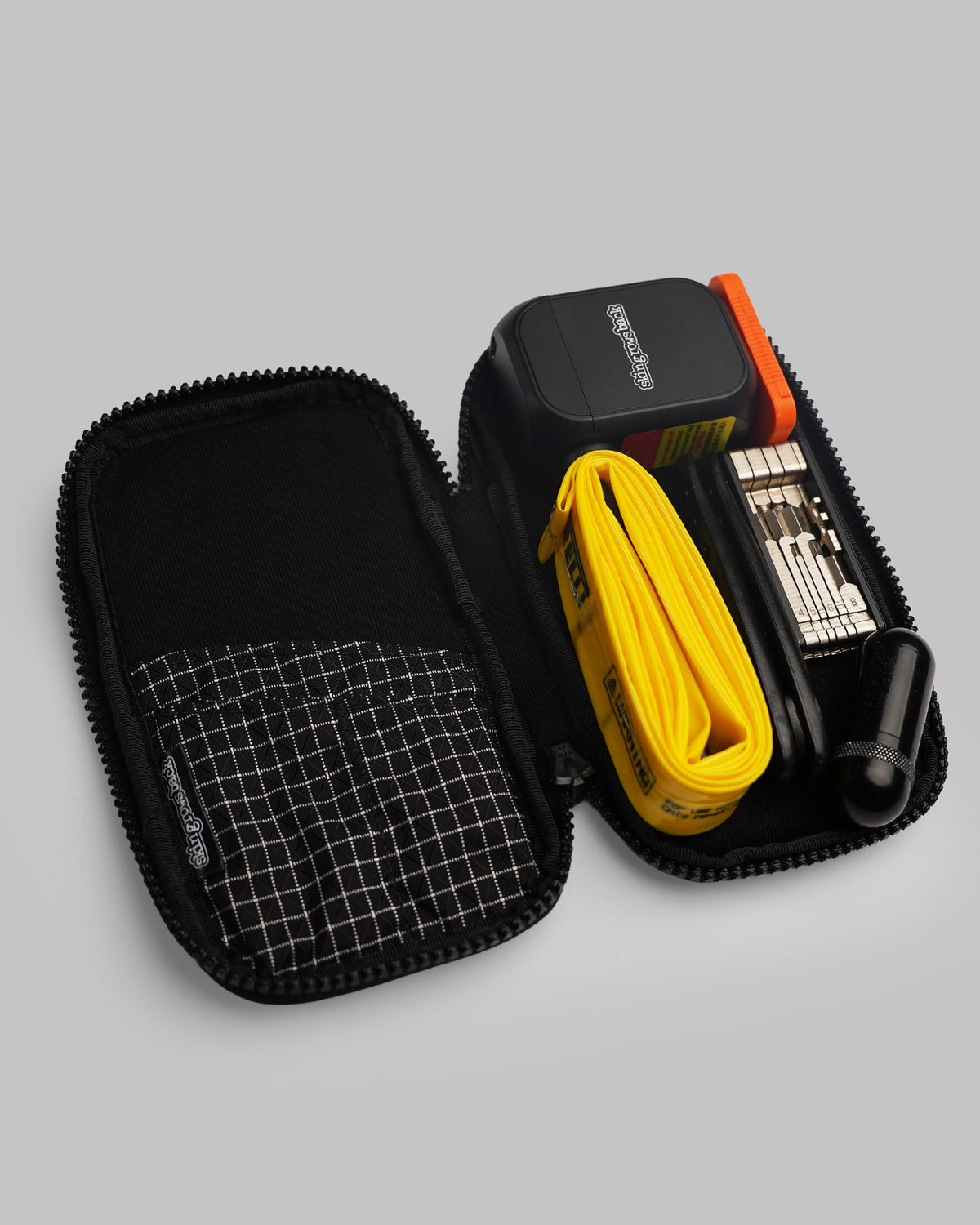skingrowsback phone jacket with dyneema zip case open with an epump yellow tpu inner tube multi-tool orange button battery holder black tyre levers black plug kit inside on a grey background