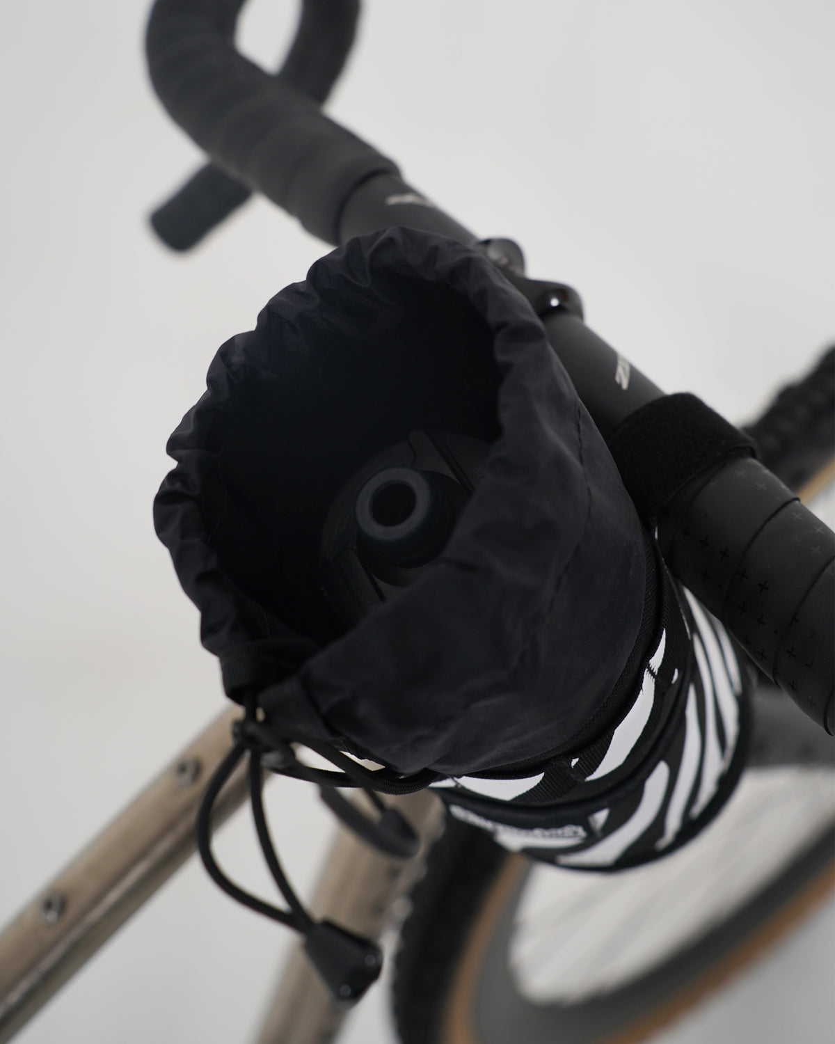 skingrowsback snack stack stem feed bag black and white zebra print on a titanium gravel bike with a white background