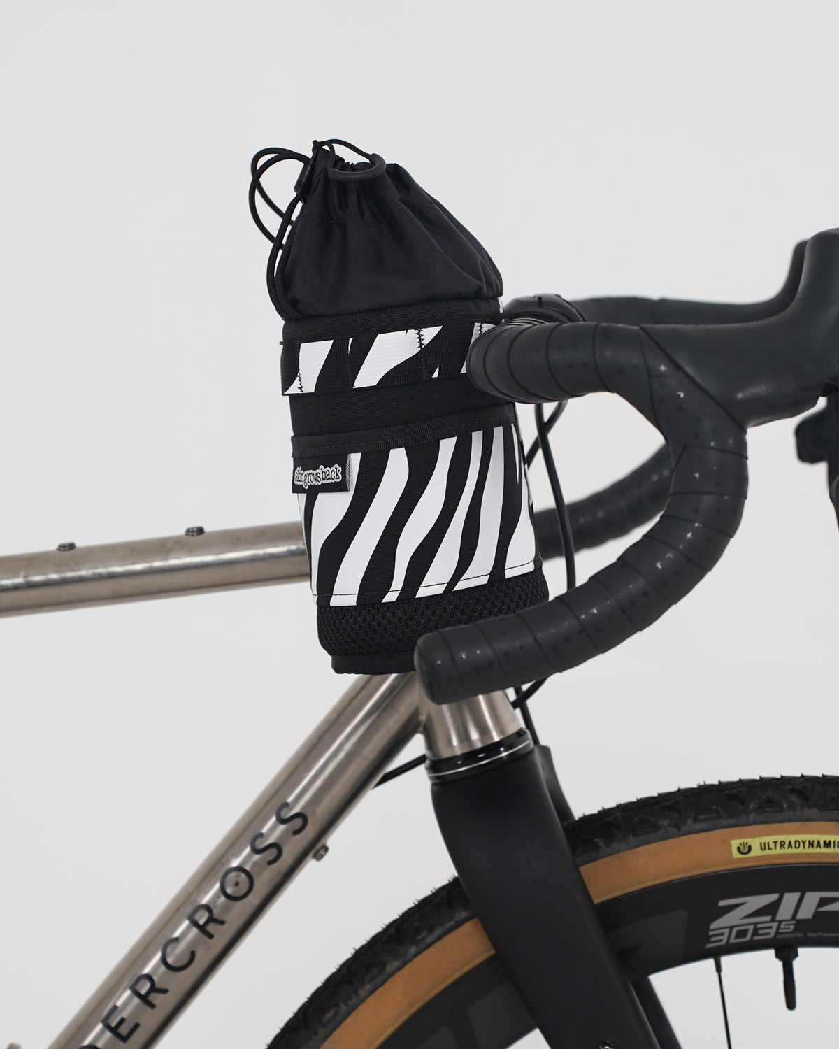 skingrowsback snack stack stem feed bag black and white zebra print on a titanium gravel bike with a white background