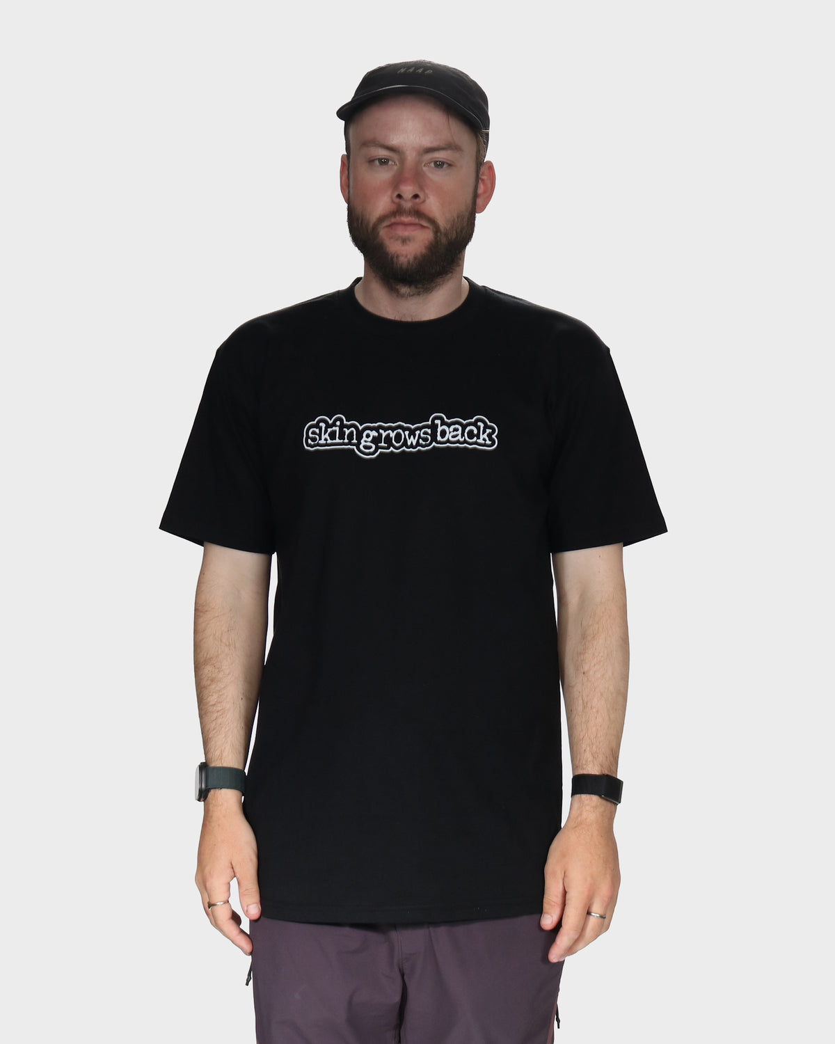 Man wearing a black t-shirt with skingrowsback logo in white background
