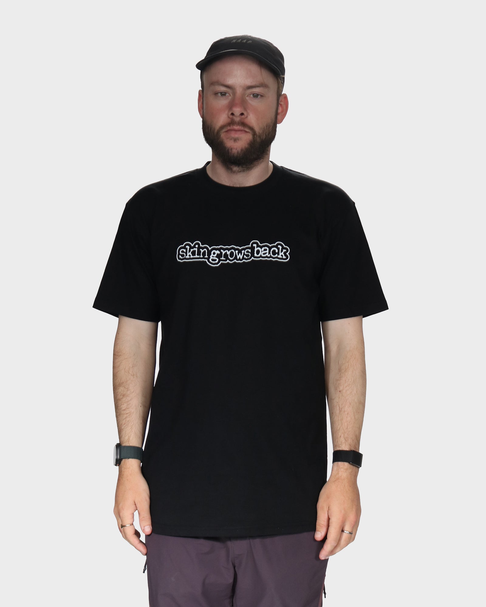 Man wearing a black t-shirt with skingrowsback logo in white background