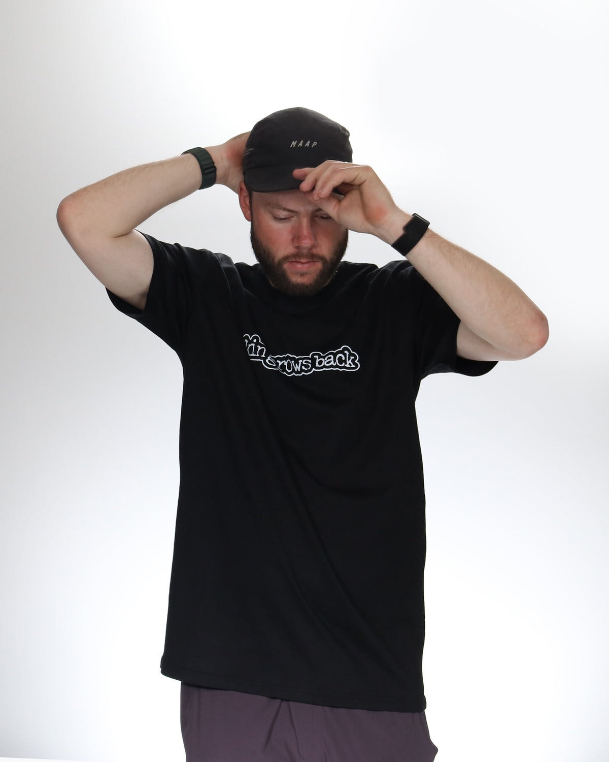Man wearing a black t-shirt with skingrowsback logo in white background