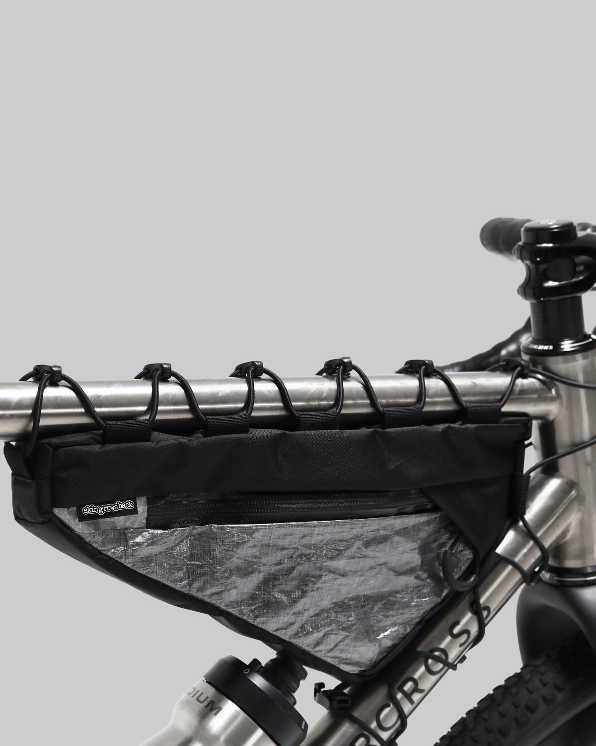 Skingrowsback Wedge Racing frame bag black xpac vx21 silver dyneema on a titanium gravel bike close up on a grey background