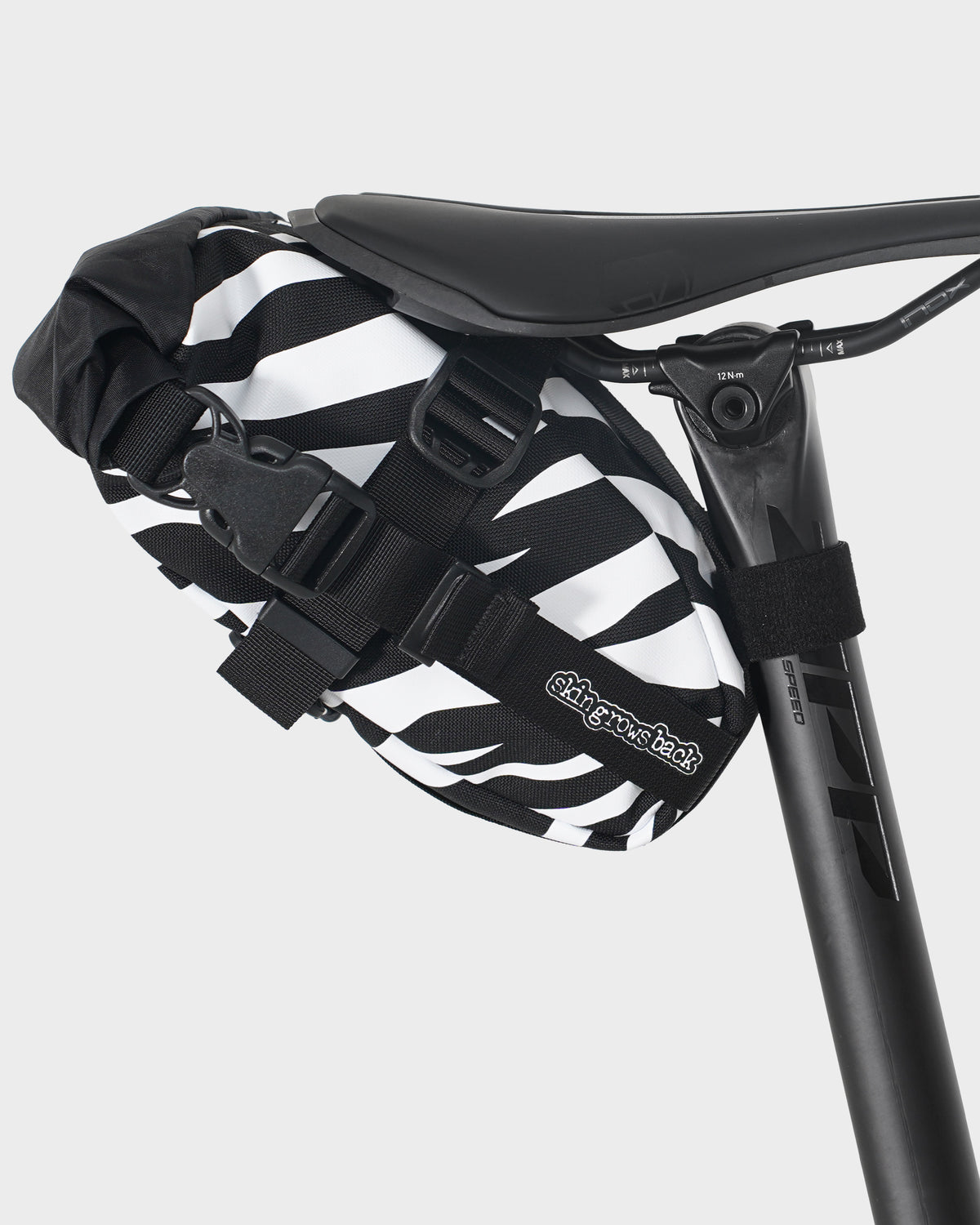skingrowsback flash pak saddle bag black and white zebra print on a black bike saddle with a white background