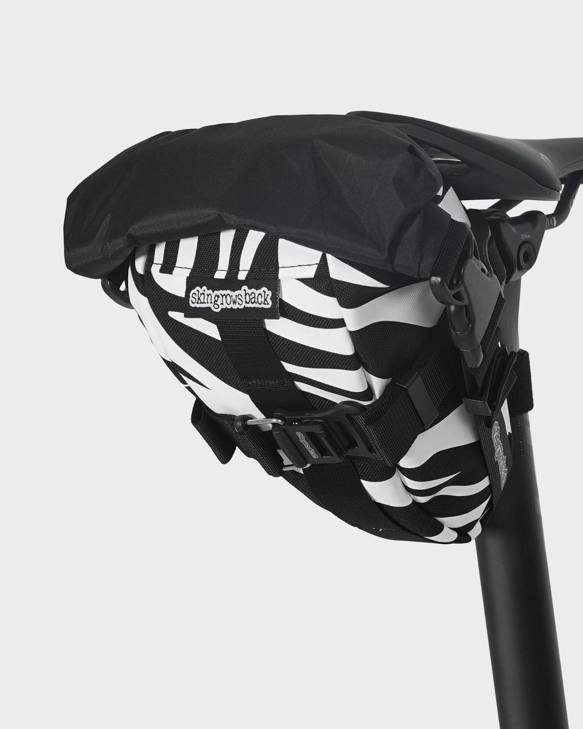 skingrowsback flash pak saddle bag black and white zebra print on a black bike saddle with a white background