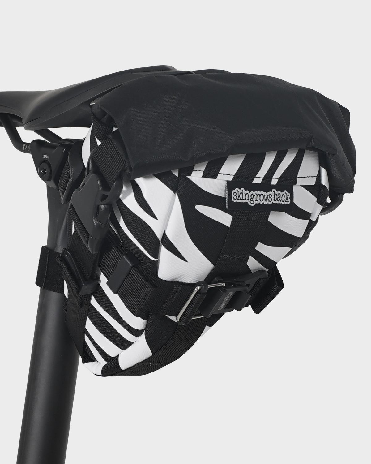 skingrowsback flash pak saddle bag black and white zebra print on a black bike saddle with a white background