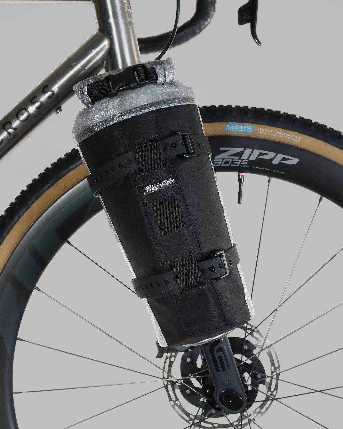 Skingrowsback transcend racing series moai bikepacking fork bag black xpac vx21 with silver dyneema on a titanium gravel bike close up against a grey background
