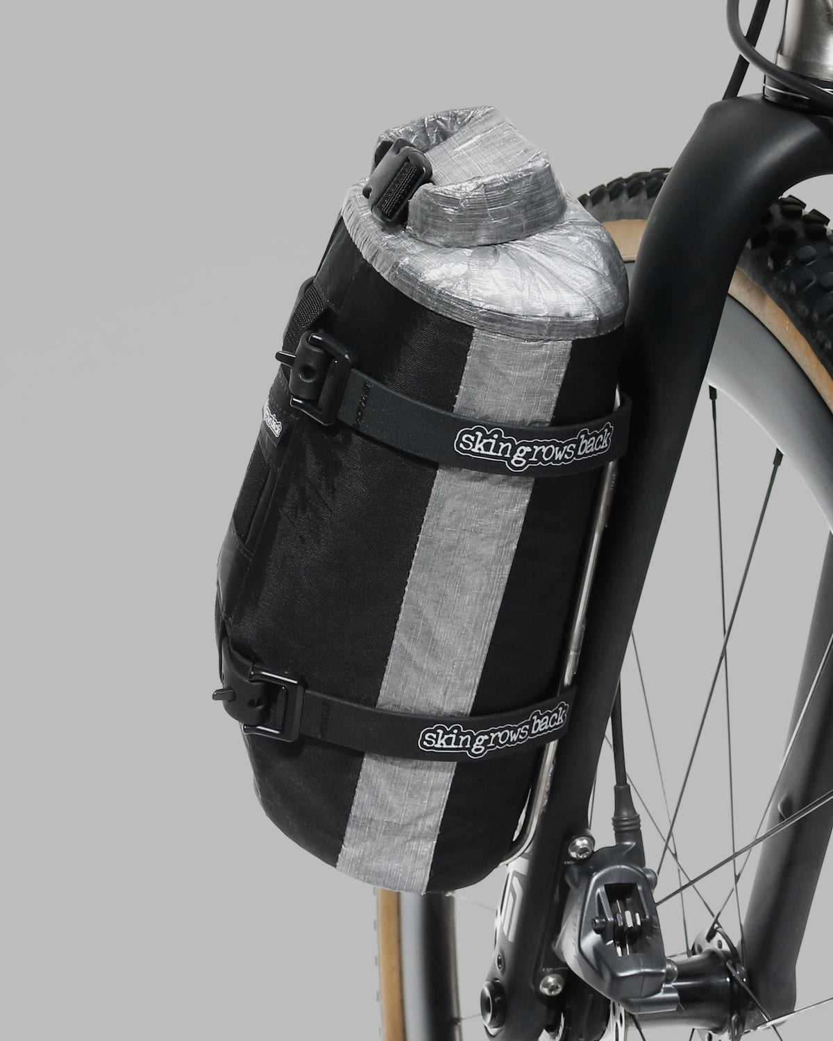 Skingrowsback transcend racing series moai bikepacking fork bag black xpac vx21 with silver dyneema on a titanium gravel bike close up against a grey background