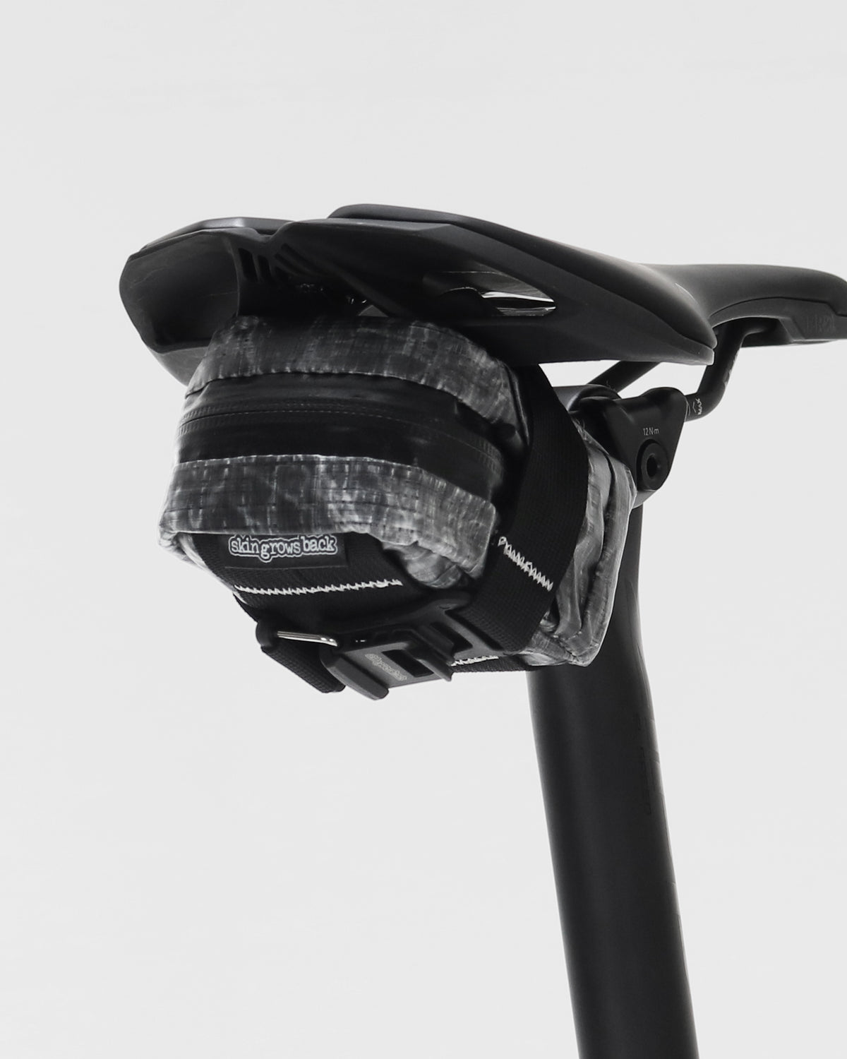 skingrowsback plan b micron saddle bag dyneema black on a black bicycle seat and seatpost against a white background