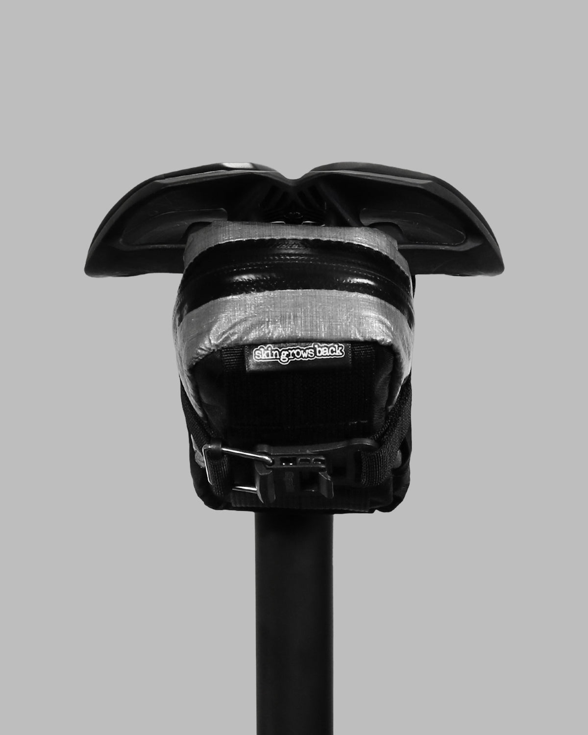 Skingrowsback plan b micron racing saddle bag black xpac vx21 plus reflective dyneema on a black bike seat with a grey background