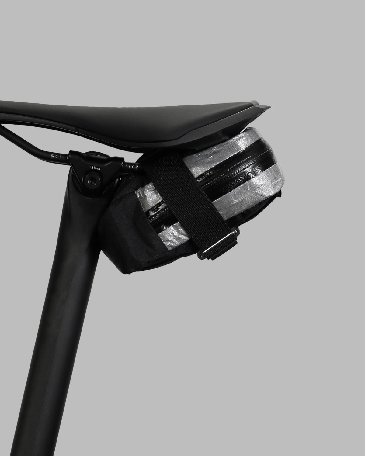 Skingrowsback plan b micron racing saddle bag black xpac vx21 plus reflective dyneema on a black bike seat with a grey background