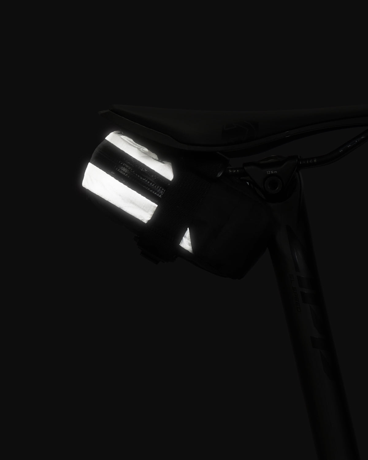 Skingrowsback plan b micron racing saddle bag black xpac vx21 plus reflective dyneema on a black bike seat against a black backgroud