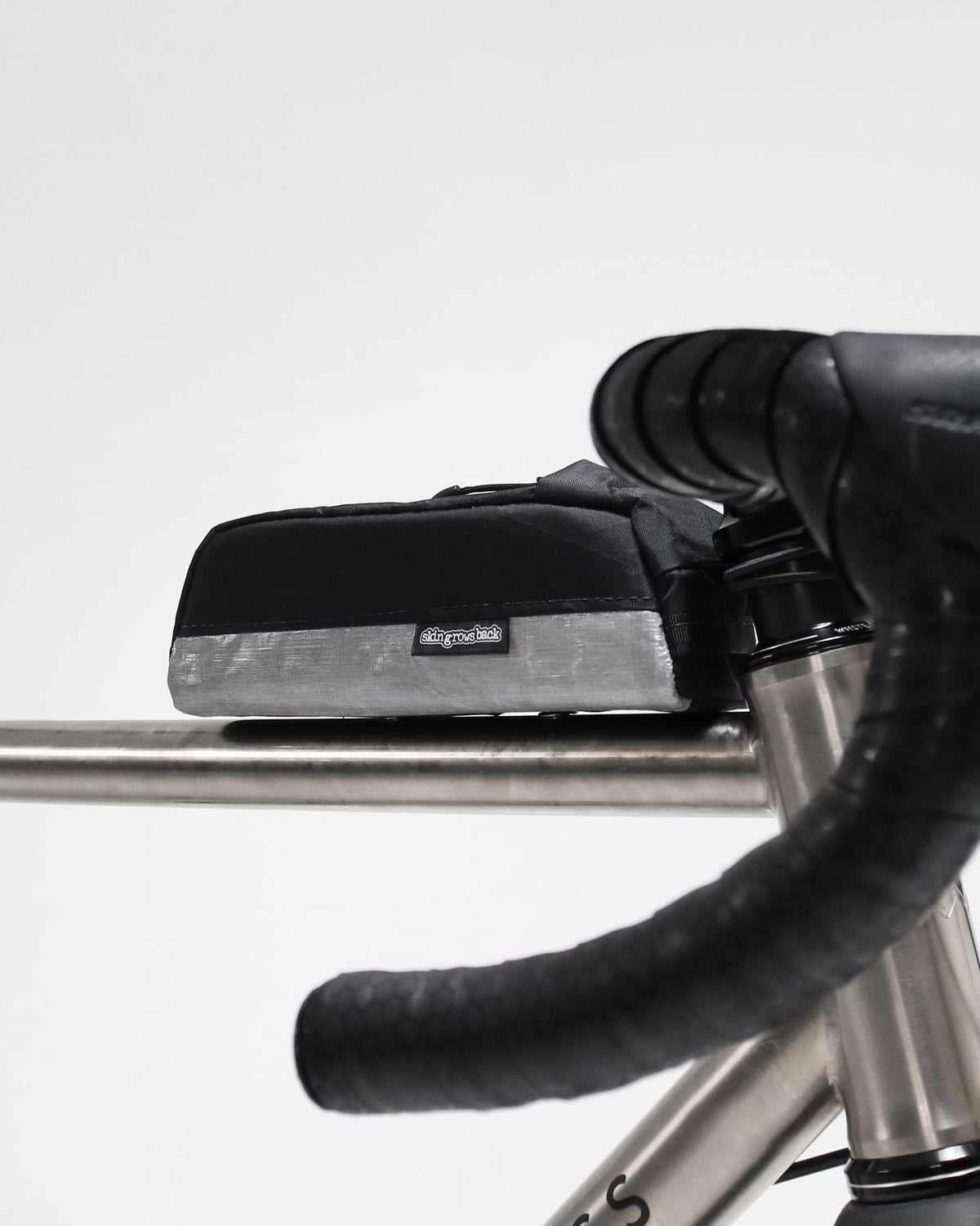 Skingrowsback Shortie Racing top tube bag bolt on black xpac vx21 silver dyneema on a titanium gravel bike on a white background
