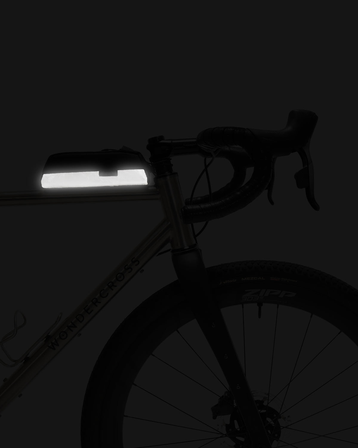 Skingrowsback shortie racing bolt on top tube bag on a gravel bike showing the reflective panel with a dark background