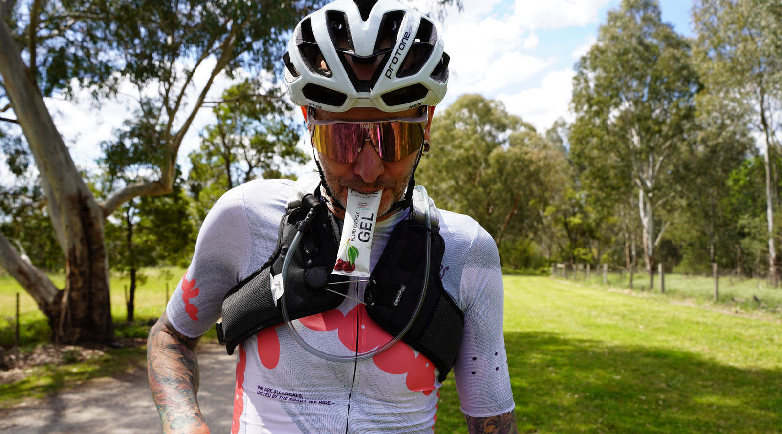 Skingrowsback Transcend Racing Series 1.5 Litre Hydration Backpack — male cyclist riding on Australian gravel road taking a gel